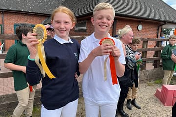 a girl and boy displaying their prize ribbons