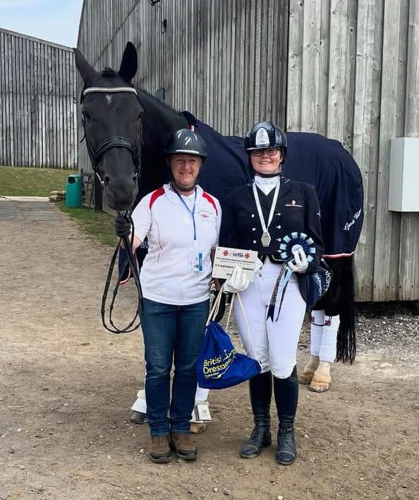 two people standing next to a horse